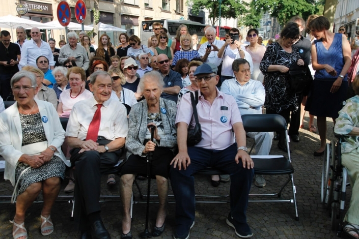 ältere Menschen sitzen auf Stühlen im Freien