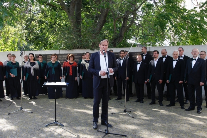 Oberbürgermeister Jung hält eine Rede, dahinter steht der Leipziger Synagogalchor