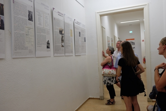 Menschen in einer Ausstellung schauen auf Schrifttafeln